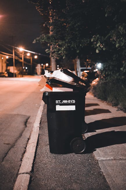 A large, chaotic pile of mixed household waste is shown in this black-and-white image, consisting of various discarded objects and materials. Prominent items include crumpled paper and cardboard, scattered across the scene, along with several plastic bottles and containers, some of which have visible labels and caps. There are crumpled plastic bags and wrinkled tissue or paper towels, contributing to the disorganized texture. The waste is heaped on a flat surface, likely outdoors or on a driveway, with some items leaning and overlapping each other. The background reveals additional clutter, suggesting this is an overflow or collection of non-recyclable refuse that might be gathered for private waste collection or removal services. The lighting appears natural, casting subtle shadows that highlight the uneven arrangement of the debris. As part of waste management practices, Rubbish Removal Chelsea would manage the proper disposal or collection of such refuse, consistent with their expertise in handling various types of household rubbish for customers seeking alternative waste solutions outside local authority collections.